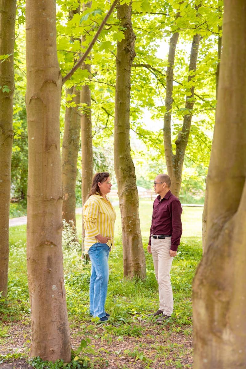 Twee volwassenen praten tussen bomen in een groen park