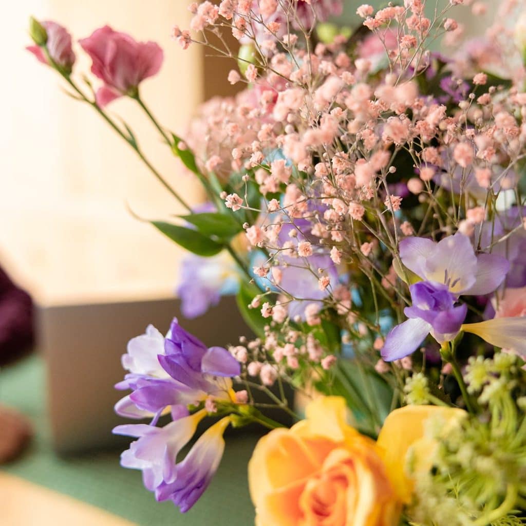 Close-up van een boeket met roze gipskruid, paarse freesia's en gele roos