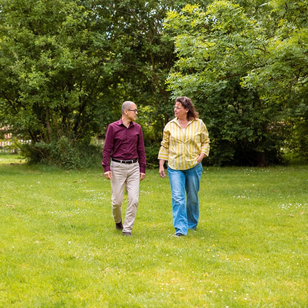 Twee mensen wandelen en praten over een grasveld in een groen park